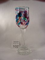 Full shot of a wine goblet with a tall stem and colorful confetti glass pattern on the bowl.