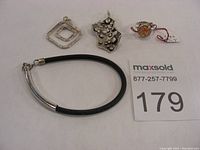 Photo showing the overall jewellery lot including two pendants, ring, geometric pendant and necklace bracelet.