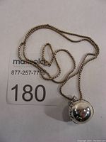 Full view of sterling silver globe pendant necklace with chain and lot number 180.