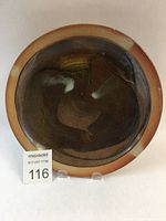 Top view of a single wood-fired ceramic plate showing its earthy glaze colors and glossy finish