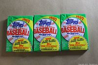 Front view of three unopened 1987 Topps Major League Baseball wax packs showing the colorful graphics, Topps logo, and promotional contest info.