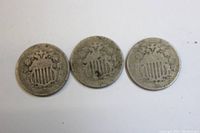 Three Shield Nickels obverse side showing shield design with dates 1866, 1867 and one indeterminate.