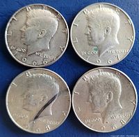 Obverse side of four Kennedy Half Dollar coins dated 1966, 1967, and two 1968s, showing the profile of John F. Kennedy.