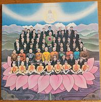 Front cover of the George Harrison 1974 "Dark Horse" album showing colorful artwork with men in suits on a pink lotus flower and mountains.