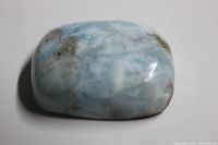 Close-up photo of a rectangular blue and white Larimar cabochon with brown matrix inclusions.