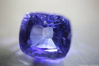 Close-up photo of the cushion cut light blue sapphire gemstone with visible facets and internal clarity.