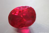 Close-up of oval cut red ruby showing rich red color and faceting details.