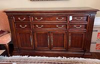 Front view of walnut buffet sideboard showing three drawers and four cabinet doors with fluted column accents.