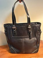 Front exterior view of black leather Coach tote handbag