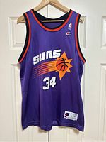 Full frontal view of the purple jersey showing the front Suns logo, number 34, Champion logo and sizing tag.