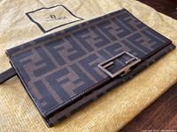 Angled exterior view showing front flap, Zucca monogram canvas and metal push-lock closure