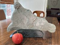 Full view of walrus sculpture on base with apple for scale