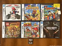 All six Nintendo DS games displayed in two rows; shows front covers and a game cartridge in center