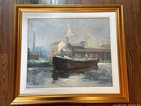 Full view of framed oil painting showing gold wood frame, white mat, canal boat scene