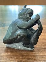 Side view of Inuit fisherman soapstone carving showing figure holding fish with detailed facial features.