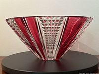 Full side view of flared red and clear crystal bowl on black surface