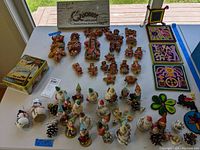 Full view of Ecuadorian bread figure ornaments, yarn art trivets, vintage metal candy box, pinecone gnome and Santa figurines arranged on a table
