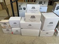Stack of ten boxes from Department 56 Heritage Village Collection with various accessory names visible on the boxes.