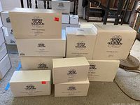 Nine Heritage Village Collection Department 56 boxes stacked on carpet showing item names and collection logo.