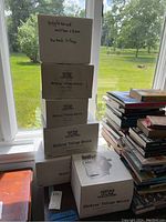 Stack of 6 white boxes labeled "Dickens' Village Series" with handwritten note "Giggleswick Mutton + Ham Dickens Village" on the top box.