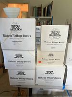 Seven boxed porcelain buildings from Department 56 Dickens' Village Series stacked showing titles on the boxes