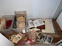 Photo showing assorted bins filled with vintage paper ephemera, valentines, postcards, stacks of papers, and books