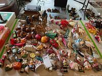 Overview of assorted vintage glass Christmas ornaments and figurines arranged on table showing varied shapes, colors, and materials.