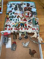 Overview of entire lot showing miniature houses, trees, marching band figurines, and various small ornaments arranged on a tray and cardboard.