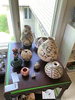 Overview of all ten pottery pieces on wooden table in front of window.