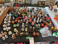 Wide view of all salt and pepper shakers on black tabletop, showing variety of designs and colors