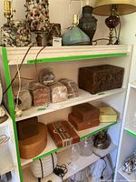 Shelving unit with various wooden and cardboard storage boxes, decorative wooden carved box, and cigar boxes wrapped in plastic