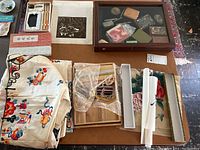 Overview of embroidered robe, scrolls and display case on table