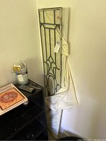 Two tall narrow vintage leaded glass window panes leaning against a wall, partially covered with white fabric.