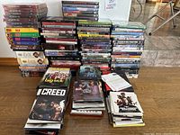 Wide view of stacked DVDs and Blu-rays on hardwood floor.