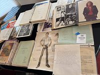 Overview of binders, scrapbooks, loose papers and sketches spread on table