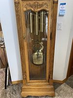Lower front view showing oak base, glass door, brass weights and pendulum
