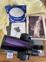 Top view of purple telescope tube with finder scope, 6 mm eyepiece, instruction manual, night sky map, astronomical calendar 1991