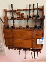 Full view of wooden pipe rack with drawers, top and bottom pipe display shelves, and pipes in slots