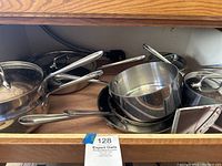 Drawer full of stacked stainless steel pans, saucepans and lids
