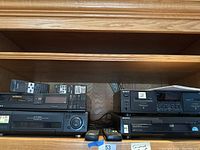 Shelf view showing two video recorders (Betamax and VHS) with two remote controls in front