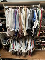 Overview of a clothing rack holding about 40 pieces of women's tops in various colors and styles, mostly long-sleeve blouses and tees size large.