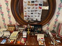 Wooden dresser top with mirror in background showing assorted jewelry laid out