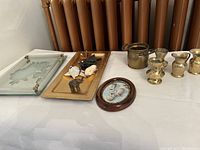 Overview of assorted decorative items on table including pitchers, bucket, figurines, framed 3D picture, and white wall piece