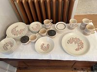 Top view of entire dish set on table showing all plates, bowls, mugs, and sugar bowl.