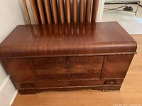 Front view of polished wooden cedar chest with decorative molding.