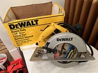 DeWalt heavy duty 7 1/4 inch circular saw in yellow and silver with attached blade and power cord, placed next to its original box.
