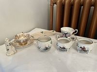 Collection of Irish china including cups, saucers, creamers, sugar bowl, and salt shaker on white cloth