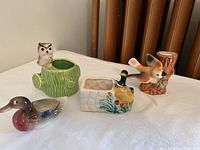 Photo of four ceramic knick knacks: owl on green log planter, rectangular planter with bird, ceramic bird figurine, and bird on stump planter.
