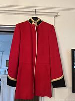 Full view of red military style jacket hanging on a hanger, showing front and collar detail.