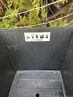 Black plastic planter pot showing inside with drainage hole and Veradek label.